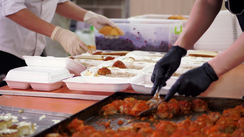 Voluntários próximos fazem refeições quentes gratuitas em lanchonetes para serem entregues a pessoas pobres e sem-abrigo durante o