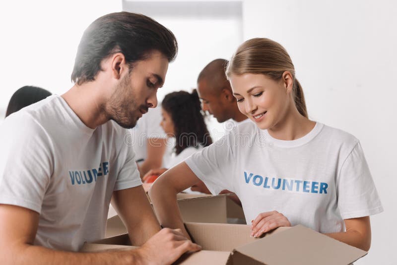 Voluntários que embalam bens na caixa fotografia de stock Voluntários que embalam bens na caixa fotografia de stock