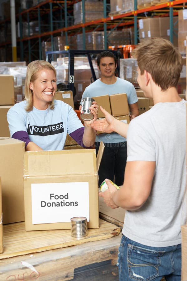 Voluntários que recolhem doações do alimento no armazém foto de stock Voluntários que recolhem doações do alimento no armazém foto de stock