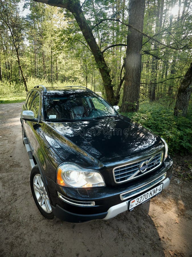 GRODNO, BELARUS - MAY 2015: Volvo XC90 4.4 v8 1st generation restyling 4WD SUV test drive in spring forest country road wide shot side vertical view with sunflares in Grodno Belarus. GRODNO, BELARUS - MAY 2015: Volvo XC90 4.4 v8 1st generation restyling 4WD SUV test drive in spring forest country road wide shot side vertical view with sunflares in Grodno Belarus