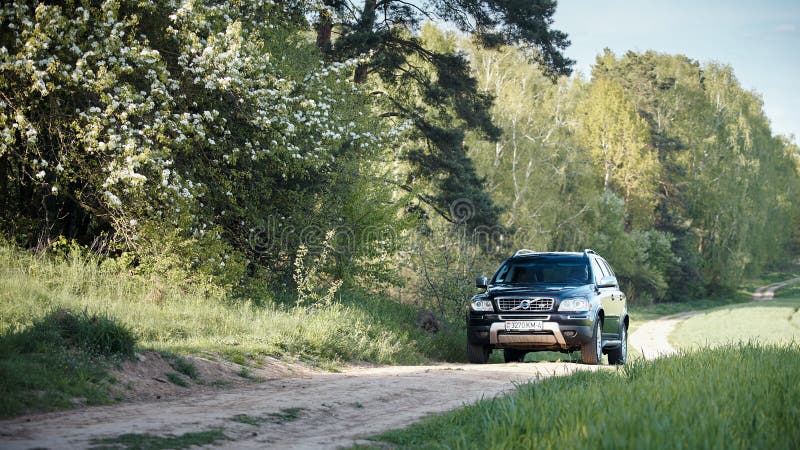 GRODNO, BELARUS - MAY 2015: Volvo XC90 4.4 v8 1st generation restyling 4WD SUV test drive in spring field country road on bloom and blossoms forest background in Grodno Belarus. GRODNO, BELARUS - MAY 2015: Volvo XC90 4.4 v8 1st generation restyling 4WD SUV test drive in spring field country road on bloom and blossoms forest background in Grodno Belarus