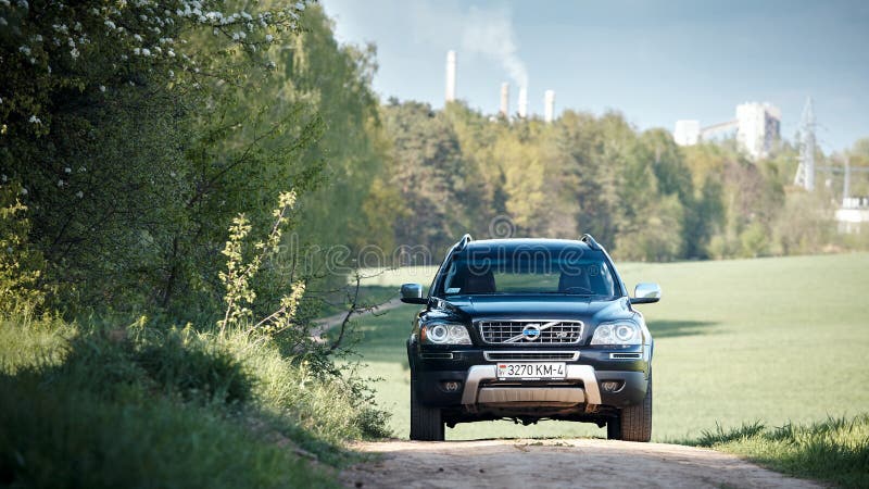 GRODNO, BELARUS - MAY 2015: Volvo XC90 4.4 v8 1st generation restyling 4WD SUV test drive in spring field country road on forest background with tubes and smoke in Grodno Belarus. GRODNO, BELARUS - MAY 2015: Volvo XC90 4.4 v8 1st generation restyling 4WD SUV test drive in spring field country road on forest background with tubes and smoke in Grodno Belarus