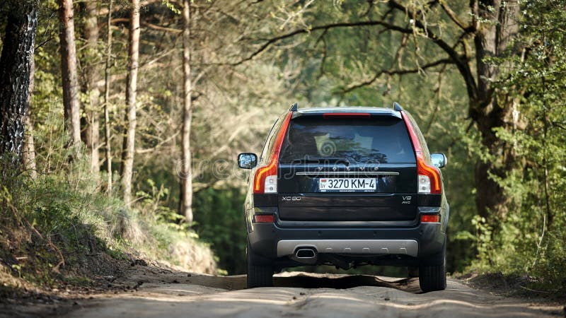 GRODNO, BELARUS - MAY 2015: Volvo XC90 4.4 v8 1st generation restyling 4WD SUV test drive in spring country bumped road with on forest background back view in Grodno Belarus. GRODNO, BELARUS - MAY 2015: Volvo XC90 4.4 v8 1st generation restyling 4WD SUV test drive in spring country bumped road with on forest background back view in Grodno Belarus