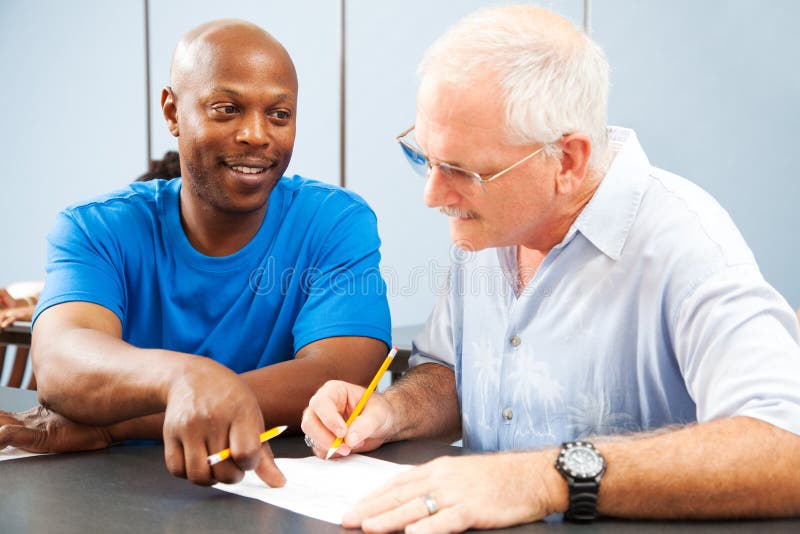 Young college student tutoring an older classmate. Young college student tutoring an older classmate.