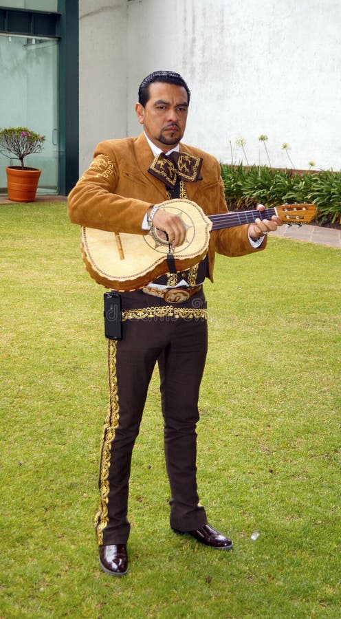 Volwassen mannelijke Mariachi die zijn kleine gitaar in een Mexicaans huwelijk spelen stock foto Volwassen mannelijke Mariachi die zijn kleine gitaar in een Mexicaans huwelijk spelen stock foto