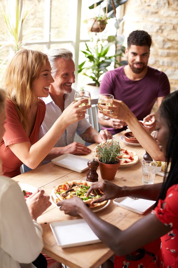 Volwassen vrienden die in een koffie eten die een verticale toost maken, stock foto Volwassen vrienden die in een koffie eten die een verticale toost maken, stock foto