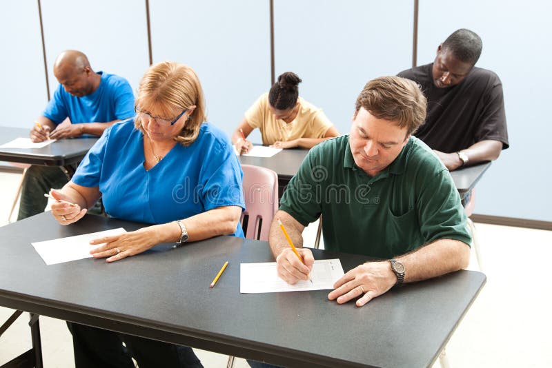 Classrom of adult education students taking a test in school . Focus on the guy in the front. Classrom of adult education students taking a test in school . Focus on the guy in the front.