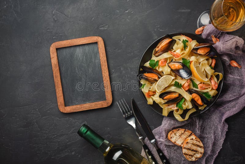 Vongole спагетти, итальянские макаронные изделия морепродуктов с clams и мидии, в плите с травами и стеклом белого вина на дереве стоковые фотографии rf Vongole спагетти, итальянские макаронные изделия морепродуктов с clams и мидии, в плите с травами и стеклом белого вина на дереве стоковые фотографии rf