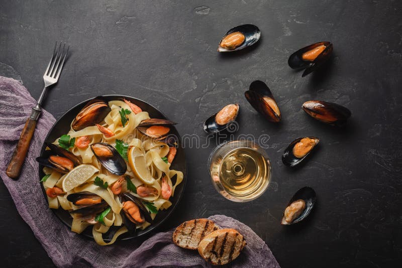 Vongole спагетти, итальянские макаронные изделия морепродуктов с clams и мидии, в плите с травами и стеклом белого вина на дереве стоковые фотографии rf Vongole спагетти, итальянские макаронные изделия морепродуктов с clams и мидии, в плите с травами и стеклом белого вина на дереве стоковые фотографии rf