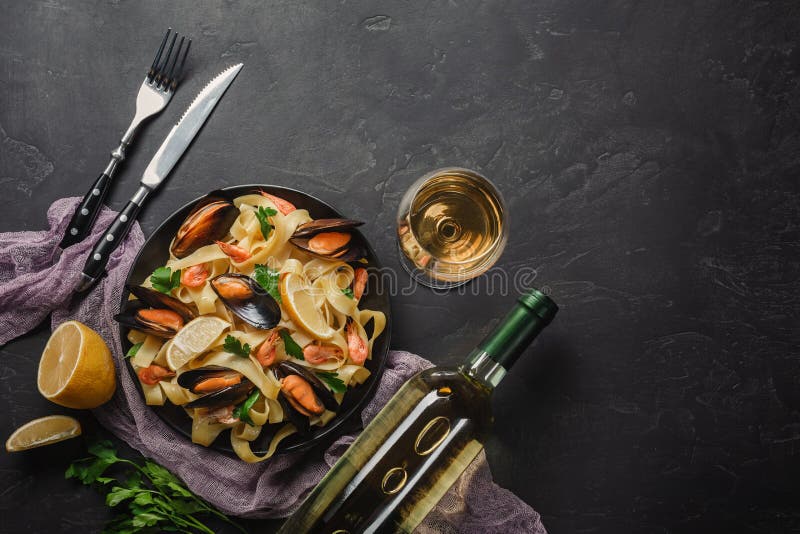 Vongole dos espaguetes, massa italiana do marisco com moluscos e mexilhões, na placa com ervas e vidro do vinho branco na pedra r imagens de stock royalty free Vongole dos espaguetes, massa italiana do marisco com moluscos e mexilhões, na placa com ervas e vidro do vinho branco na pedra r imagens de stock royalty free