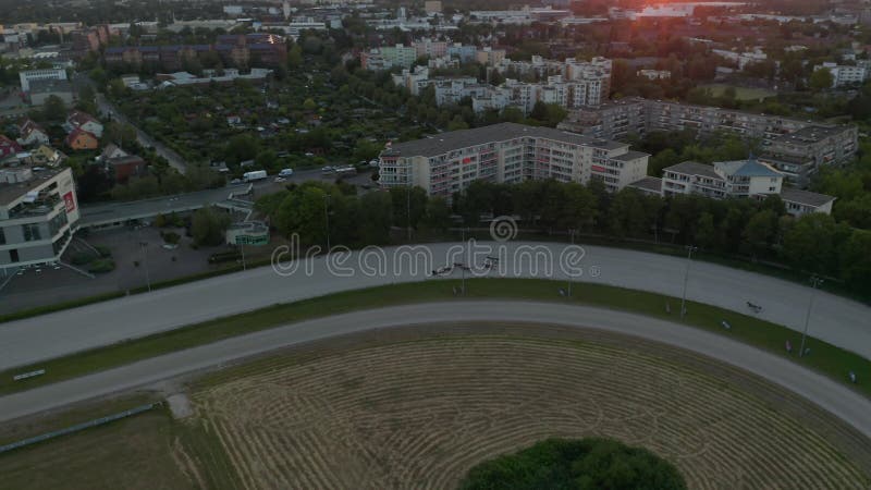 Voo que estabelece um tiro na corrida de cavalos de harness na pista de terra na perspectiva do drone de luz solar de cima