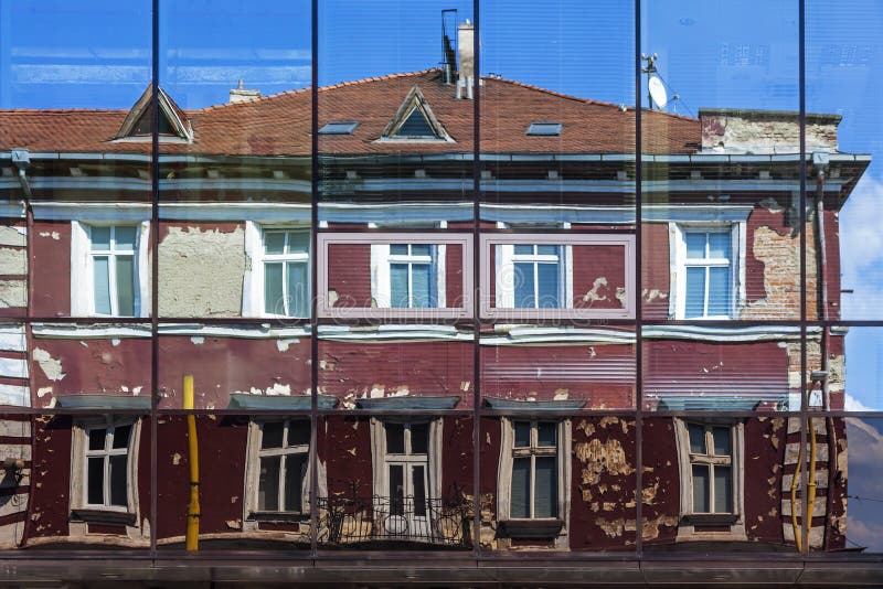 Voorgevel van de oude die bouw in de vensters van modern Hotel wordt weerspiegeld stock fotografie Voorgevel van de oude die bouw in de vensters van modern Hotel wordt weerspiegeld stock fotografie