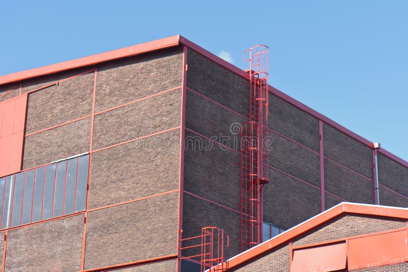 Voorzijde van een grote fabriek met aardige rode details stock foto Voorzijde van een grote fabriek met aardige rode details stock foto