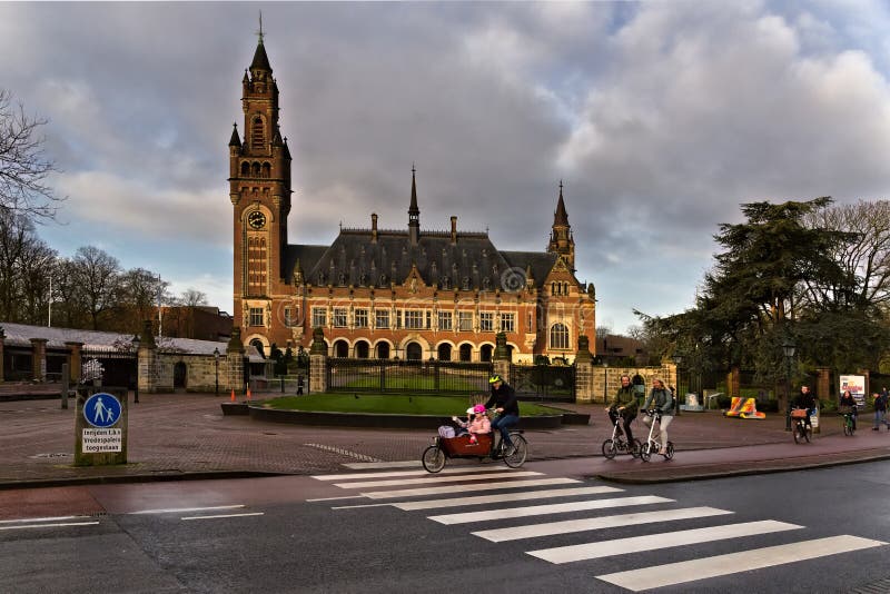 Various commuters pass in front of the Peace Palace in the early morning. Cycling is the most popular mode of transportation in the netherlands. Adults and children from all walks of life commutie to work and school on the bike. Various commuters pass in front of the Peace Palace in the early morning. Cycling is the most popular mode of transportation in the netherlands. Adults and children from all walks of life commutie to work and school on the bike.