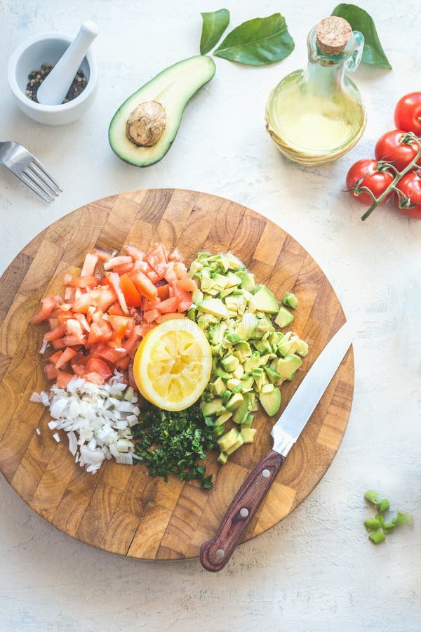 Vorbereitung des geschmackvollen frischen Avocadotomaten-Salsasalats auf Draufsicht des weißen Küchentischhintergrundes. Hackfleis stockfoto