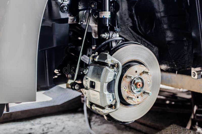 Vordere Scheibenbremse auf Auto im Prozess des neuen Reifenersatzes stockfotografie Vordere Scheibenbremse auf Auto im Prozess des neuen Reifenersatzes stockfotografie