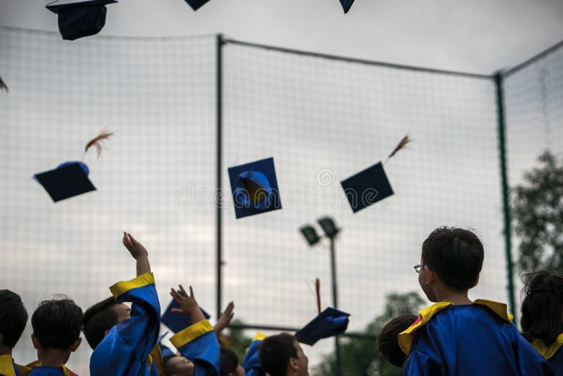 Preschool kids wearing graduated dress throwing cap and diplomat in sky in graduated celebration day. Preschool kids wearing graduated dress throwing cap and diplomat in sky in graduated celebration day..