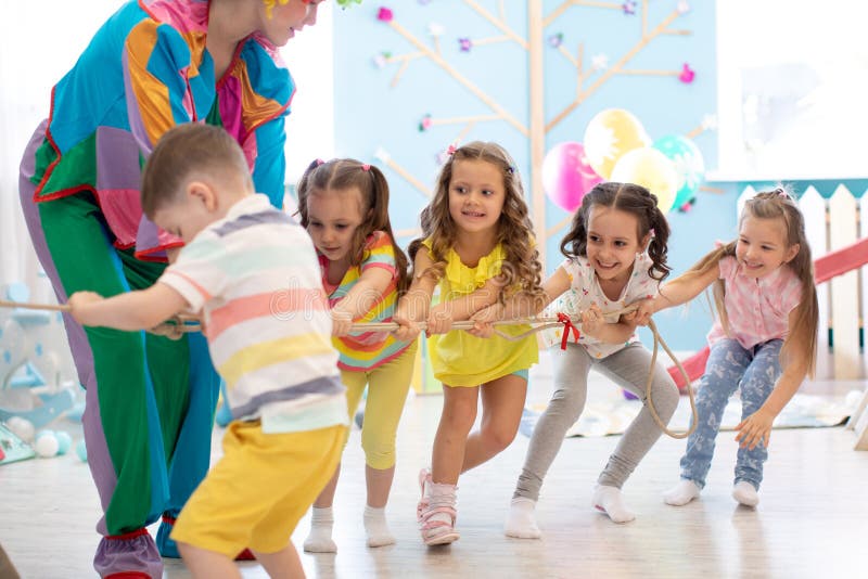 Vorschulkinder spielen Teamspiel mit Clown lizenzfreie stockfotos Vorschulkinder spielen Teamspiel mit Clown lizenzfreie stockfotos