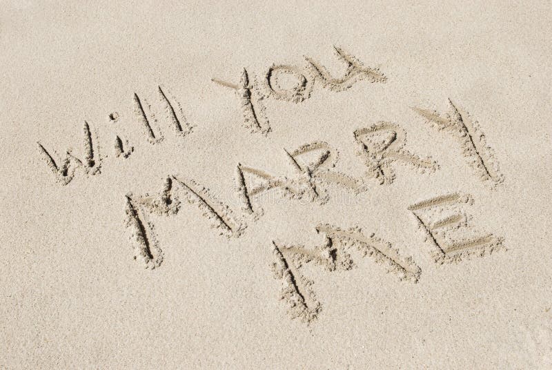 The words Will You Marry Me written in sand, horizontal with copy space. The words Will You Marry Me written in sand, horizontal with copy space