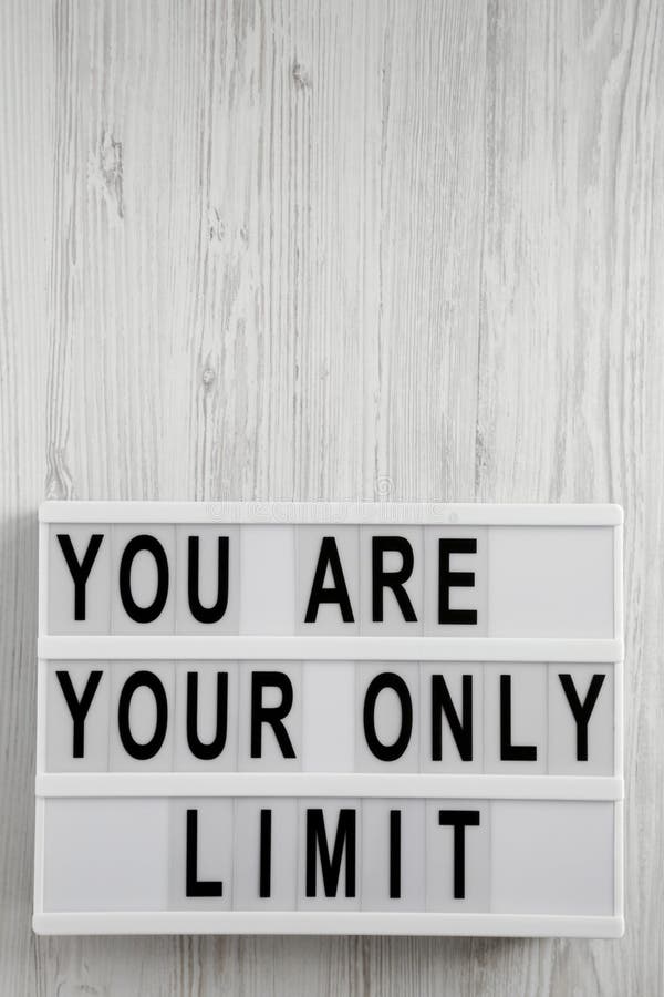 `You are your only limit` words on a lightbox over white wooden background, top view. Overhead, from above. Flat lay. Copy space.