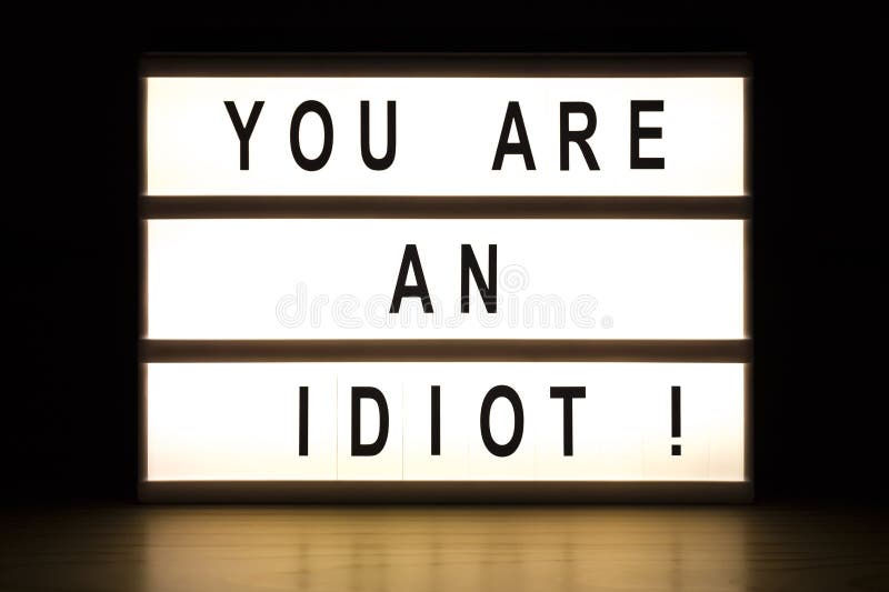 You are an idiot light box sign board on wooden table. You are an idiot light box sign board on wooden table.