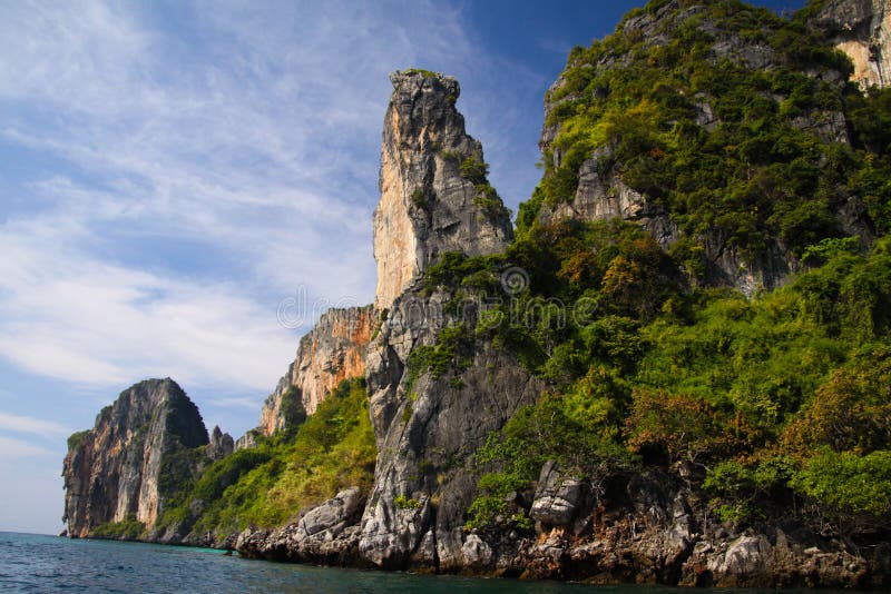 Voyage de bateau suivant la ligne de côte de l'île tropicale Ko Phi Phi le long des formations de roche impressionnantes sous le image libre de droits Voyage de bateau suivant la ligne de côte de l'île tropicale Ko Phi Phi le long des formations de roche impressionnantes sous le image libre de droits