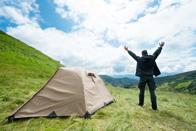 Voyageur heureux dans les montagnes près de la tente images stock Voyageur heureux dans les montagnes près de la tente images stock