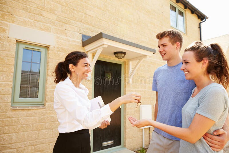 Female real estate agent giving keys to new property owners. Female real estate agent giving keys to new property owners