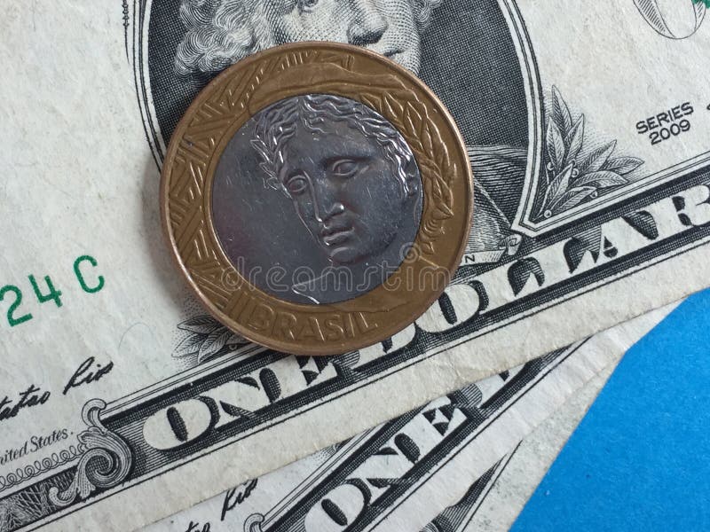 Brazilian real coin and US dollar banknotes on blue background. Brazilian real coin and US dollar banknotes on blue background