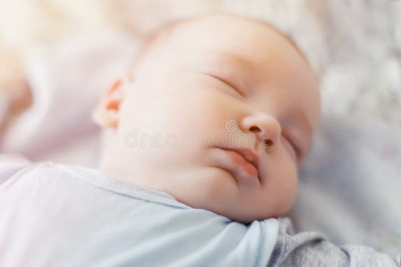 Vreedzame baby die op een bed liggen terwijl het slapen in een heldere ruimte stock afbeeldingen Vreedzame baby die op een bed liggen terwijl het slapen in een heldere ruimte stock afbeeldingen