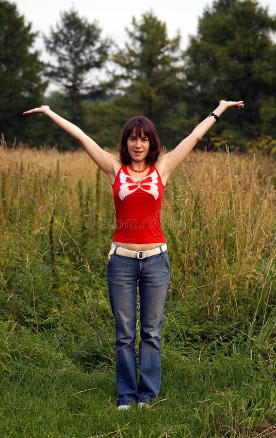 Brown-haired young woman showing joy and happyness at the middle of summer meadow. Brown-haired young woman showing joy and happyness at the middle of summer meadow