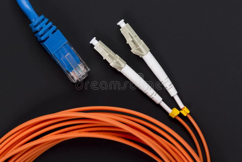 Vridna blått parar lappkabel med orange kabel för fiberoptik på mörk bakgrund arkivfoton Vridna blått parar lappkabel med orange kabel för fiberoptik på mörk bakgrund arkivfoton