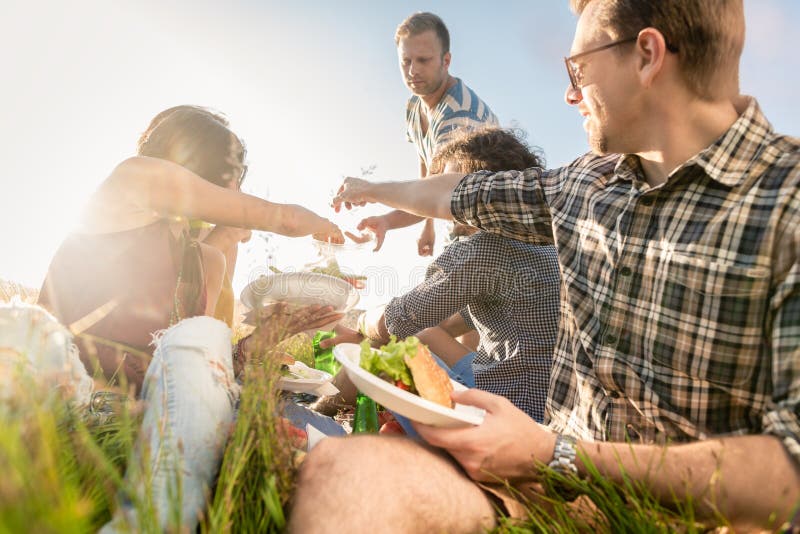 Vrienden die de zomerbbq picknick hebben en samen eten royalty-vrije stock afbeeldingen Vrienden die de zomerbbq picknick hebben en samen eten royalty-vrije stock afbeeldingen