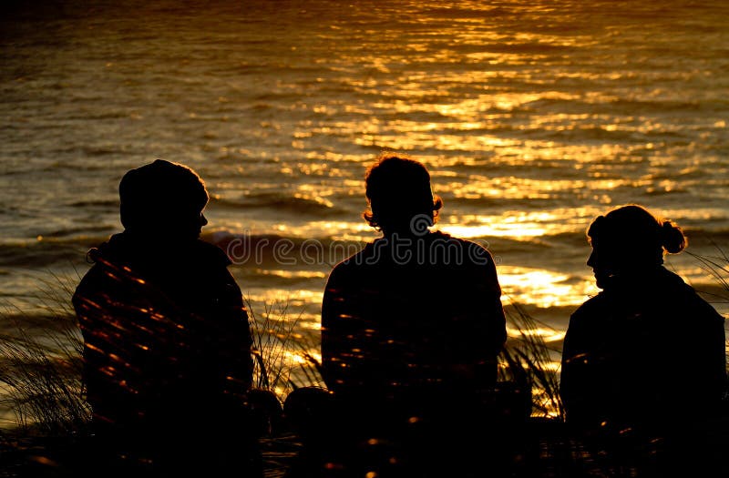 Vrienden die op duin in zonsondergang zitten stock foto's Vrienden die op duin in zonsondergang zitten stock foto's