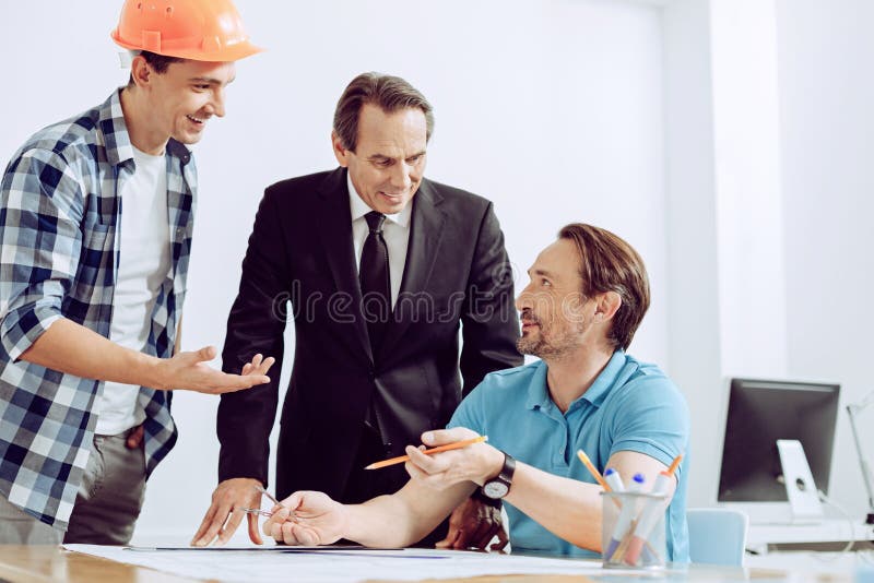 Vriendschappelijke collega's die een opwindend verhaal bespreken op het werk stock afbeelding Vriendschappelijke collega's die een opwindend verhaal bespreken op het werk stock afbeelding