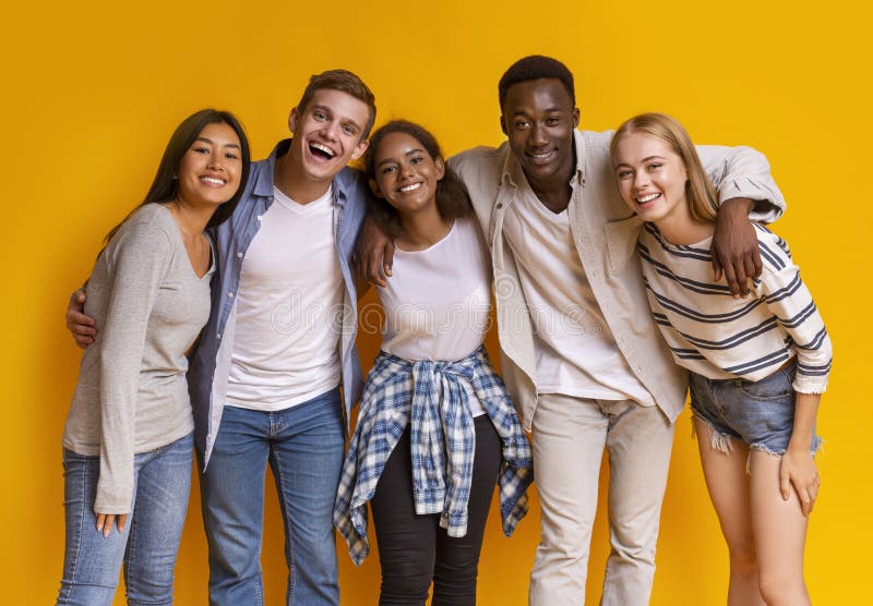 Vriendschappelijke groep internationale studenten die glimlachen over gele achtergrond