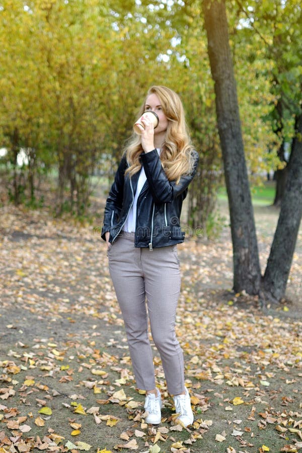 Vrij het Jonge Vrouw Lopen in Autumn Park Relax Drinking Coffee haalt Kop weg stock afbeelding Vrij het Jonge Vrouw Lopen in Autumn Park Relax Drinking Coffee haalt Kop weg stock afbeelding