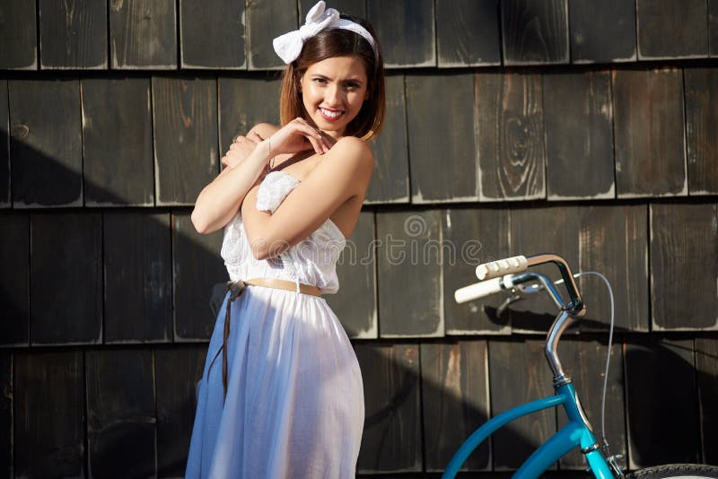 Vrij het vrouwelijke stellen met blauwe fiets dichtbij donkere houten muur stock afbeelding Vrij het vrouwelijke stellen met blauwe fiets dichtbij donkere houten muur stock afbeelding