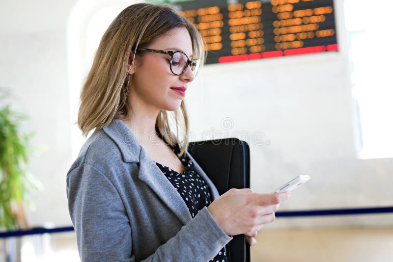 Vrij jonge bedrijfsvrouw die haar mobiele telefoon in het station met behulp van royalty-vrije stock afbeelding Vrij jonge bedrijfsvrouw die haar mobiele telefoon in het station met behulp van royalty-vrije stock afbeelding