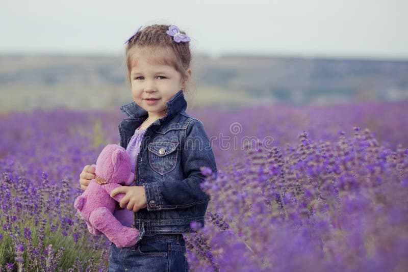 Vrij jonge meisjeszitting op lavendelgebied in aardige hoedenschipper met purpere bloem op het stock fotografie Vrij jonge meisjeszitting op lavendelgebied in aardige hoedenschipper met purpere bloem op het stock fotografie
