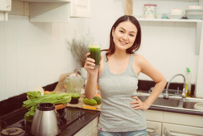 Vrij jonge vrouw die een plantaardige smoothie in haar keuken drinken royalty-vrije stock afbeelding Vrij jonge vrouw die een plantaardige smoothie in haar keuken drinken royalty-vrije stock afbeelding