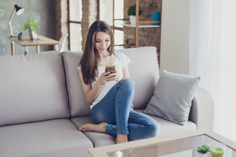 Vrij jonge vrouwenzitting op laag thuis en typend sms aan hij royalty-vrije stock fotografie Vrij jonge vrouwenzitting op laag thuis en typend sms aan hij royalty-vrije stock fotografie