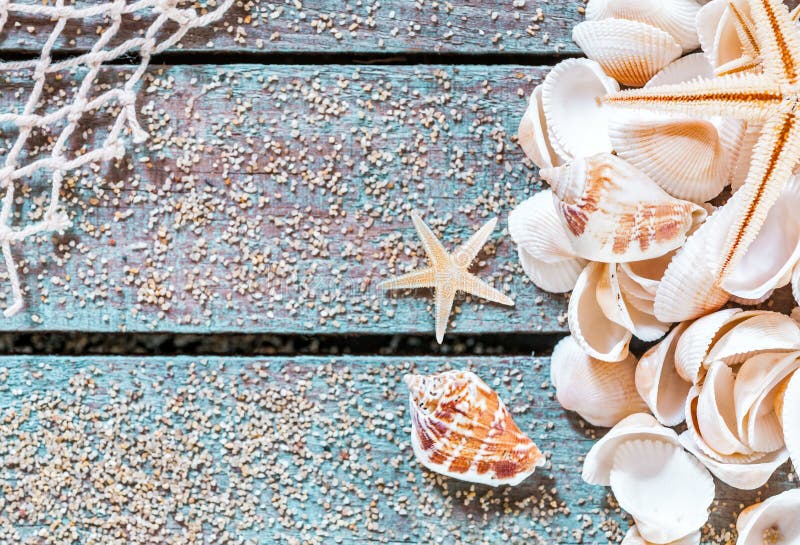 Pretty nautical card design with seashells and a starfish on blue painted boards covered with scattered golden sea sand and fishing net decorating one corner with central copyspace. Pretty nautical card design with seashells and a starfish on blue painted boards covered with scattered golden sea sand and fishing net decorating one corner with central copyspace