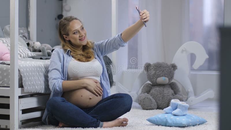 Vrij zwangere vrouw die selfies met telefoon maken