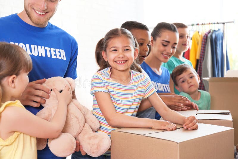 Vrijwilligers met kinderen die schenkingsgoederen sorteren stock fotografie Vrijwilligers met kinderen die schenkingsgoederen sorteren stock fotografie