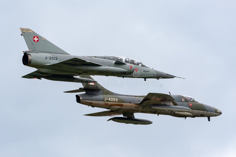 Vroegere Swiss Air-Luchtspiegeling III vechtersvliegtuigen j-2012 van Krachtdassault hb-RDF die in vorming met een Venter Hunter stock afbeeldingen Vroegere Swiss Air-Luchtspiegeling III vechtersvliegtuigen j-2012 van Krachtdassault hb-RDF die in vorming met een Venter Hunter stock afbeeldingen