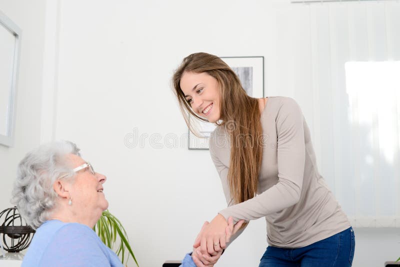 Vrolijk jong meisje die oude hogere vrouw behandelen bij haar huis stock fotografie Vrolijk jong meisje die oude hogere vrouw behandelen bij haar huis stock fotografie