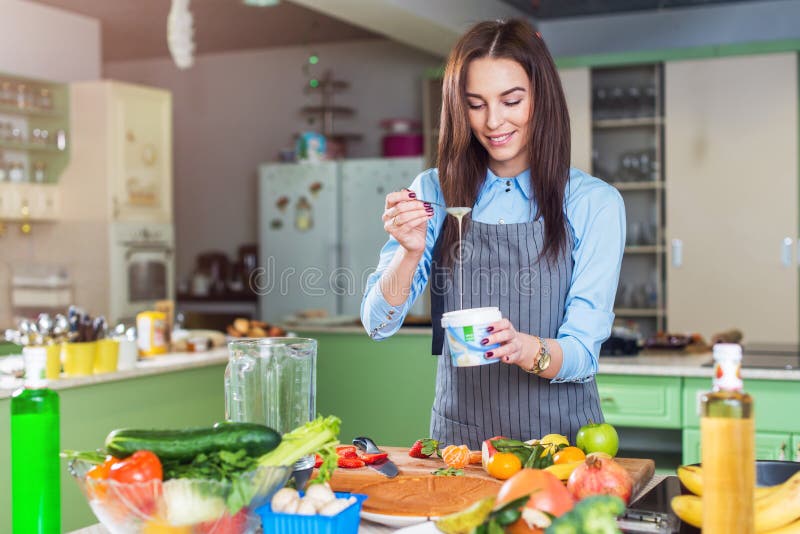 Vrolijk jong vrouwelijk chef-kok kokend dessert die condens in schotel in haar keuken toevoegen royalty-vrije stock afbeeldingen Vrolijk jong vrouwelijk chef-kok kokend dessert die condens in schotel in haar keuken toevoegen royalty-vrije stock afbeeldingen