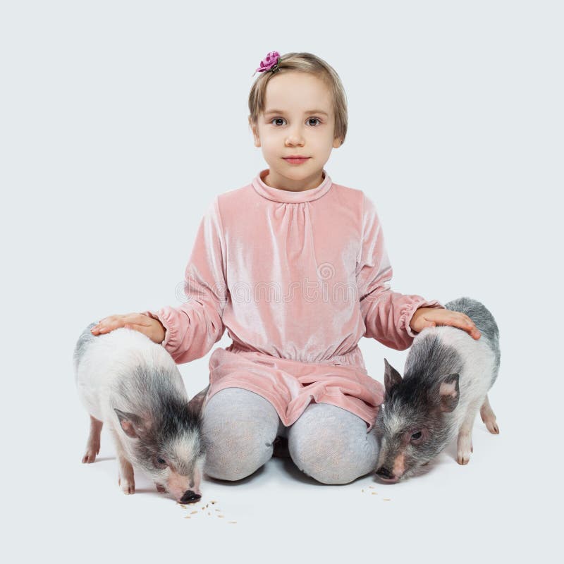 Vrolijk weinig kindmeisje en varkens Kind en huisdieren stock foto's Vrolijk weinig kindmeisje en varkens Kind en huisdieren stock foto's