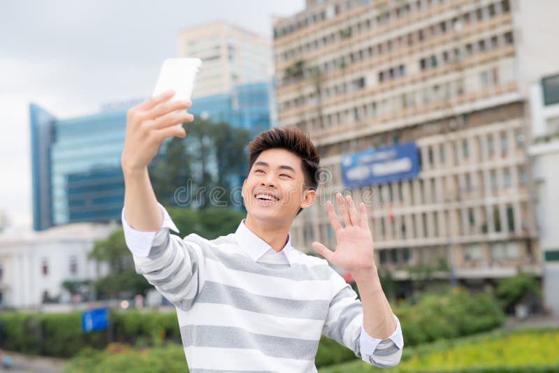 Vrolijke Aziatische mens die selfie op moderne smartphone nemen terwijl het genieten van van prettige gang in openbaar park, port stock afbeeldingen Vrolijke Aziatische mens die selfie op moderne smartphone nemen terwijl het genieten van van prettige gang in openbaar park, port stock afbeeldingen